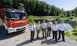 Tobias Starke (v.l., Bevölkerungsschutz Kreis Paderborn), Matthias Berndt, Christoph Wiegand, Helmut Birkenfeld (alle Regionalforstamt Hochstift), Stefan Nostitz (Kreisbrandmeister im Kreis Höxter) und Daniel Wulf (Leitstelle Höxter) stehen am Löschteich "Bodental" bei Altenbeken. - Niklas Tüns