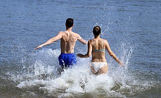Ein Mann und eine Frau laufen ins kühle Wasser. Nach eher durchwachsenem Wetter ist nun reichlich Sonne angekündigt. - picture alliance/dpa