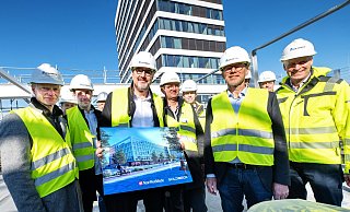 Mit Nachbar H1 im Hintergrund und Bild vom fertigen NW-Neubau: Geschäftsführer Klaus Schrotthofer (Mitte), Verlagsleiter Axel Walker und Goldbeck-Geschäftsführer Jörg-Uwe (vorn, v. r.) und Bauteam beim Richtfest auf der Dachterrasse des sechsgeschossigen Neubaus. - Barbara Franke