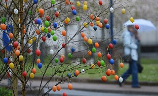 Bunte Ostereier bewegen sich an einem Baum im stürmischen Wind. - picture alliance / dpa