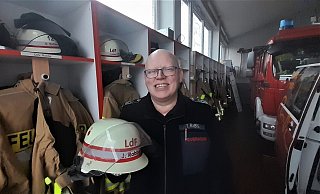 Jürgen Rabbe im Gerätehaus seines Heimatortes Ossendorf, wo sein Spind neben dem seines Bruder liegt. In der Hand hält er den Helm mit dem rot-silber-roten Band, das ihn als Mitglied des Kreisbrandmeister-Teams ausweist. - Simone Flörke