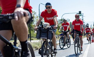 Benedikt Goesmann ist mit Hund Bruno im Körbchen nach über 5.000 Kilometern auf dem Rad planmäßig in Santiago de Chile angekommen und wird dort von der DKMS vor Ort in Empfang genommen. - Jean Paul Osses