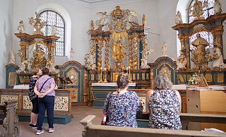 Einige Besucherinnen der Paderborner Liborikapelle halten vor dem geschnitzten Hochaltar inne. - Niklas Tüns