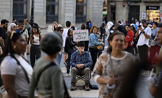 Barcelona im November 2024: Ein Aktivist auf dem Plaza de Sant Jaume in Barcelona zeigt ein Schild mit der Aufschrift 'Tourists go home''. - picture alliance / NurPhoto