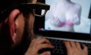 Ein Mann schaut auf einen Laptop-Bildschirm mit expliziten Inhalten – ein Symbolbild für den Kampf gegen Sexsucht. - picture alliance/dpa