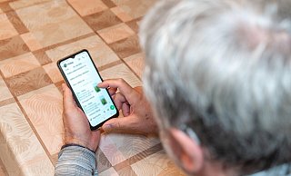 Ein älterer Mann überprüft Nachrichten auf seinem Smartphone – Online-Betrug wird zunehmend zur Gefahr. - picture alliance / CHROMORANGE