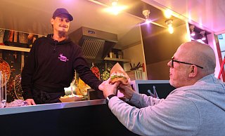 Frank Schmidt bekommt seinen Burger am Stand von Sebastian Müller. - amoschner