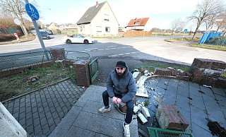 Anwohner Mahmud Fakih sitzt auf den Trümmern seiner Gartenmauer. Zweimal sind Autos bei Unfällen auf der Kreuzung in die Grundstücksbegrenzung gekracht. - Ulf Hanke