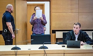 Der Angeklagte verdeckt vor den Fotografen im Gerichtssaal sein Gesicht. - Neue Westfälische