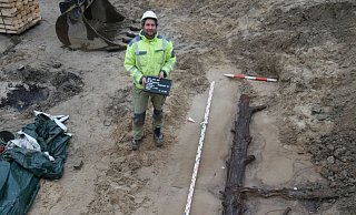 Ein Grabungsarbeiter zeigt im März die Ausmaße eines der entdeckten Baumstämme. - EggensteinExca