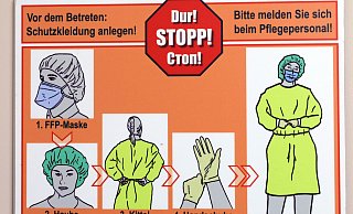 Ein Warnschild zeigt, wie Schutzkleidung angelegt wird. - Frank-Michael Kiel-Steinkamp,Frank-Michael Kiel-Steinkamp