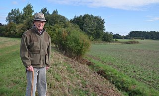 Heinz Heienbrok steht am Hasenpatt und blickt auf den Graben, an dessen Böschung bislang viele Brombeer- und Schlehenbüsche, aber zum Beispiel auch Wildrosen gestanden haben. Die sind jetzt bis auf die Grasnarbe gestutzt worden. - Mareike Patock