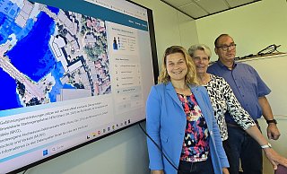 KBB-Chefin Manuela Handke (von links), Bürgermeisterin Susanne Rutenkröger und Bereichsleiter Michael Böke-Hasselmeier zeigen auf der Karte als Beispiel die Gefährdung des Rathauses, wo zumindest der Parkplatz zur Else hin bei Starkregen regelmäßig überschwemmt ist. - Gerald Dunkel