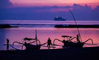 Männer befestigen vor Sonnenaufgang am Tag vor Beginn des G20-Gipfels am Strand von Nusa Dua Boote. Im Hintergrund ist ein Schiff der indonesischen Marine zu sehen. - Christoph Soeder/dpa