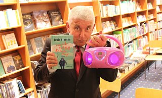 Stolz präsentiert der Kabarettist und Autor Erwin Grosche sein neues Buch. Auf der dazugehörigen Lesung hilft ihm seine pinke 'Partymaschine' bei der musikalischen Untermalung. - Moritz Jülich