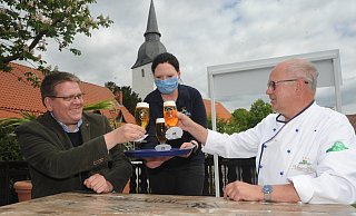 Jennifer Weitzmann servierte auf dem Leverner Stiftshügel frisch gezapftes Barre-Pils. Stemwedes Bürgermeister Kai Abruszat (l.) und Gastronom Rüdiger Meyer-Pilz stießen auf die Lockerungen für das Gastgewerbe an. - Joern Spreen-Ledebur