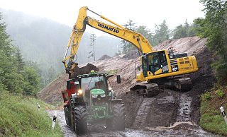 Mit dem Bagger wird der überschüssige Boden Schicht für Schicht abgetragen, damit der Hang gesenkt werden kann. - Janet König