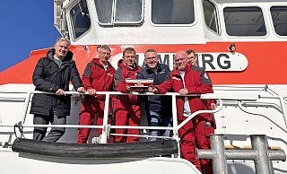 Vormann Michael Haack (3. v. l.) und seine Besatzungskollegen (v. l.) Wilm Wilms, Ralf Ulbertus und Kilian Schulz überreichen an Bord des Seenotrettungskreuzers "Hamburg" der DGzRS auf Borkum ein Sammelschiffchen an Hövelhofs Bürgermeister Michael Berens (l.) und Tourismusleiter Thomas Westhof. - Nordseeheilbad Borkum