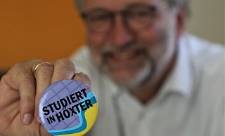 Bernd Schackers zeigt den Anstecker mit dem Kampagnen-Schriftzug „Studiert in Höxter“, der verteilt wird. - Simone Flörke