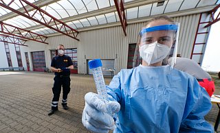 Mitarbeiter des Arbeiter-Samariter-Bunds (ASB) in Schutzkleidungen nehmen die Abstriche von rund 100 Schülern und Lehrern in der mobilen Teststation an der Feldstraße. Die Ergebnisse könnten bis zum Wochenende vorliegen. - Andreas Zobe/NW