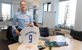 Bernd Poggemöller in seinem Büro. Er hält ein Trikot in seinen Händen, das ihm in polnischen Partnerstadt Mielec geschenkt wurde. - Dirk Windmöller