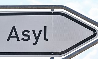 Das Wort «Asyl» steht auf einem Wegweiser zur Erstaufnahme-Einrichtungen (EAE) des Landes Brandenburg in Eisenhüttenstadt. - Patrick Pleul/dpa