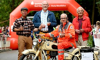 Vier Gesichter des Stadtlaufes: Ralf Aumann (v. l.), Heinz-Friedrich Heldt, Ewald Schlüter auf seiner BMW R27 und Hans-Günter Niemeier, hier zwischen Start und Ziel vor dem Rathaus bei der 40. Auflage im Juni 2025. - Jürgen Krüger