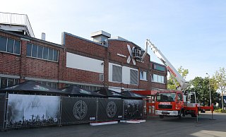 Ein Kran nimmt am Donnerstagvormittag das riesige rote X von der Fassade ab. An die Stelle soll für die Eröffnung erstmal nur ein Banner kommen. - Claus Frickemeier