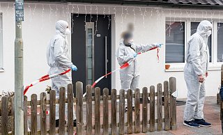 Polizeibeamte sperren mit Flatterband den Tatort ab. - Foto: Markus Scholz/dpa