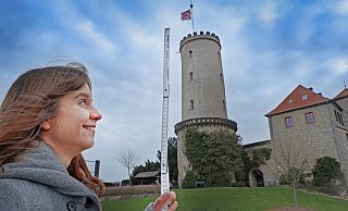 Sparrenburg-Besucherin Ann Josephine van der Does hält fürs Foto spaßeshalber einen Zollstock an. Die Vermessungs-Experten waren natürlich mit ganz anderem Kaliber am Werk und haben von verschiedenen Seiten aus gemessen. Ihr Ergebnis: Bis zur obersten Kante einer Zinne ist die Sparrenburg nicht 37 sondern nur 31,5 Meter hoch. Inklusive Fahnenmast sind's jedoch sogar 45,2 Meter. - Sarah Jonek