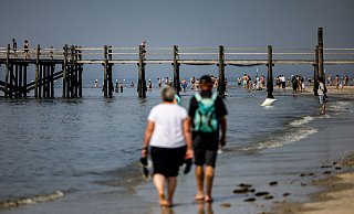 Die Sonne scheint auf den von Touristen besuchten Strand von St. Peter-Ording. - Axel Heimken/dpa