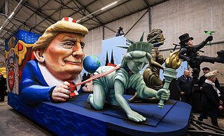 Einer der Wagen im Kölner Rosenmontagszug zeigt US-Präsident Donald Trump, der die Freiheitsstatue und die Justitia am Laufband führt. - Oliver Berg/dpa