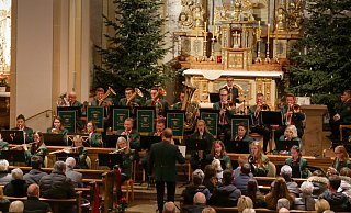 Zbigniew „Jack“ Watorowski (Mitte) dirigiert die 30 Musiker des St.-Johannes-Blasorchesters durch das Weihnachtskonzert. Neben den Zuschauerreihen sind insgesamt 25 Weihnachtssterne aufgestellt, eine Spende von Gründungsmitglied Heinrich Sander zum Jubiläumsjahr. - Kristoffer Fillies