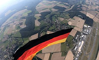 Aus der Luftperspektive ist links neben der Riesen-Flagge Wewelsburg zu sehen, oberhalb liegen Ahden und die A 44, rechts der Airport. - Cypres-Demo-Team