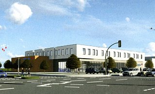 Der zweigeschossige Marktkomplex liegt abgerückt von der Straßenkante an einer deutlich verbreiterten Kreuzung. Links vor der Ampel Bruder-Konrad-Straße reihen sich drei statt zwei Autos auf. - NW