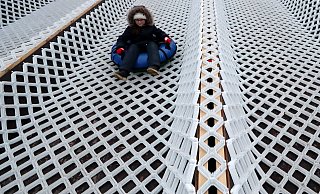 Ein Junge rutscht auf einem Schlauchring eine Rodelbahn hinab. - Themenbild: picture alliance/dpa/Alexander Demianchuk