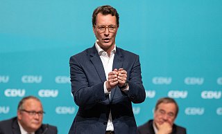 Hendrik Wüst, designierter neuer Landesvorsitzender der CDU Nordrhein-Westfalen, spricht zu den Delegierten. Hinten sitzen Generalsekretär Josef Hovenjürgen (l) und Ministerpräsident Armin Laschet. - picture alliance/dpa