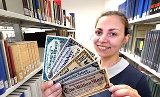 Tut nur so, als sei sie schwerreich: Güterslohs Stadtarchivarin Julia Kuklik. Sie hält ein Bündel Geldscheine, mit dem sie einst kaum einen ordentlichen Einkauf hätte tätigen können. - Andreas Frücht