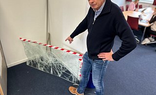 Thomas Rimpel, stellvertretender Leiter des Evangelisch Stiftischen Gymnasiums in Gütersloh, zeigt auf eine der kaputten Scheiben, die die Einbrecher offenbar mit Feuerlöschern zerstört haben. - Christian Bröder