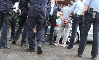 Ein Mann in Handschellen. Er wird später zum Polizeigewahrsam gebracht. Er gehört nicht zu den sechs Angeklagten sondern ist Zeuge im Prozess. - Jobst Lüdeking