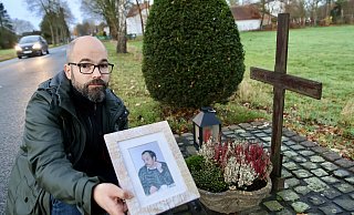 Christian Funke zeigt am Gedenkkreuz in Hövelhof ein Foto seines 1994 ermordeten Vaters Johannes Heinrich Funke. - Jens Reddeker