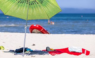 Der Sonnenschirm schützt vor der direkten Sonne, und vom Meer kommt ein laues Lüftchen. So lässt sich der Urlaub doch genießen. - Jens Büttner/dpa