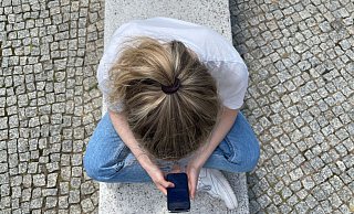 Typische Haltung in heutiger Zeit: mit gesenktem Kopf auf das Handy schauen. - Ricarda Dieckmann/dpa-tmn