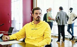 Saarbrückens Spieler Dennis Erdmann sitzt im Verhandlungssaal. Rechts im Hintergrund sind unter anderem Spieler und Funktionäre des 1. FC Magdeburg zu sehen. - picture alliance/dpa
