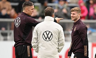 Timo Werner (r), Nico Schlotterbeck (l) und Bundestrainer Hansi Flick sprechen während einer Trainigseinheit miteinander. - Arne Dedert/dpa