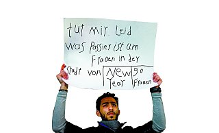 Ein Mann aus Syrien mit einem Plakat mit der Aufschrift «tut mir leid was passier ist um Köln Frauen in der Stadt von New Year» steht am 06.01.2016 in Köln (Nordrhein-Westfalen) vor dem Dom in der Nähe des Hauptbahnhofes. In der Silvesternacht hatte es rund um den Kölner Hauptbahnhof und am Dom zahlreiche sexuelle Übergriffe auf Frauen gegeben. - picture alliance / dpa