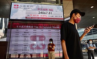 Menschen an der elektronischen Tafel einer Bank, die den Aktienindex an der Hongkonger Börse anzeigt. - Foto: Vincent Yu/AP/dpa