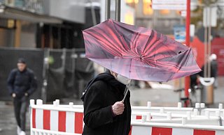 Der Regenschirm eines Passanten wird vom Sturm erfasst. Der Wetterdienst hat für heute im südlichen Nordrhein-Westfalen eine Unwetterwarnung mit orkanähnlichen Böen und Starkregen vorhergesagt. - picture alliance/dpa