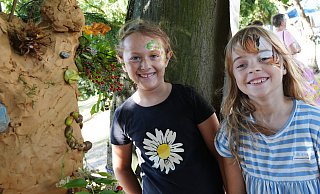 Die Freundinnen Elina (links) und Lina gestalten beim Waldfest im Dobergmuseum am Stand von Primelgrün e. V. mit Ton eine Skulptur an einem der Bäume im Garten des Bünder Museums. - GERALD DUNKEL