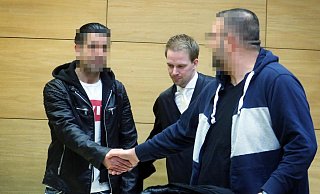 Die angeklagten Brüder (33,31) begrüßen sich am ersten Prozesstag. Dazwischen steht Verteidiger Tobias Diedrich. - Sarah Jonek
